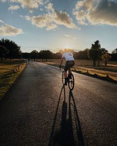 man in white shirt riding bicycle on gray asphalt road during daytime